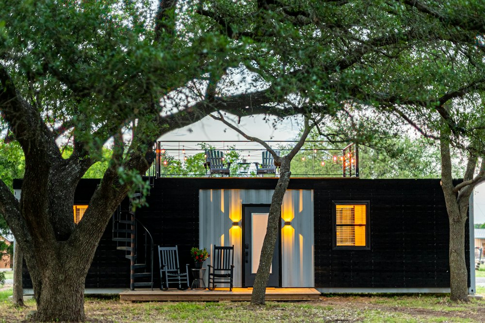 Casa prefabricada de madera oscura de un piso bajo un árbol
